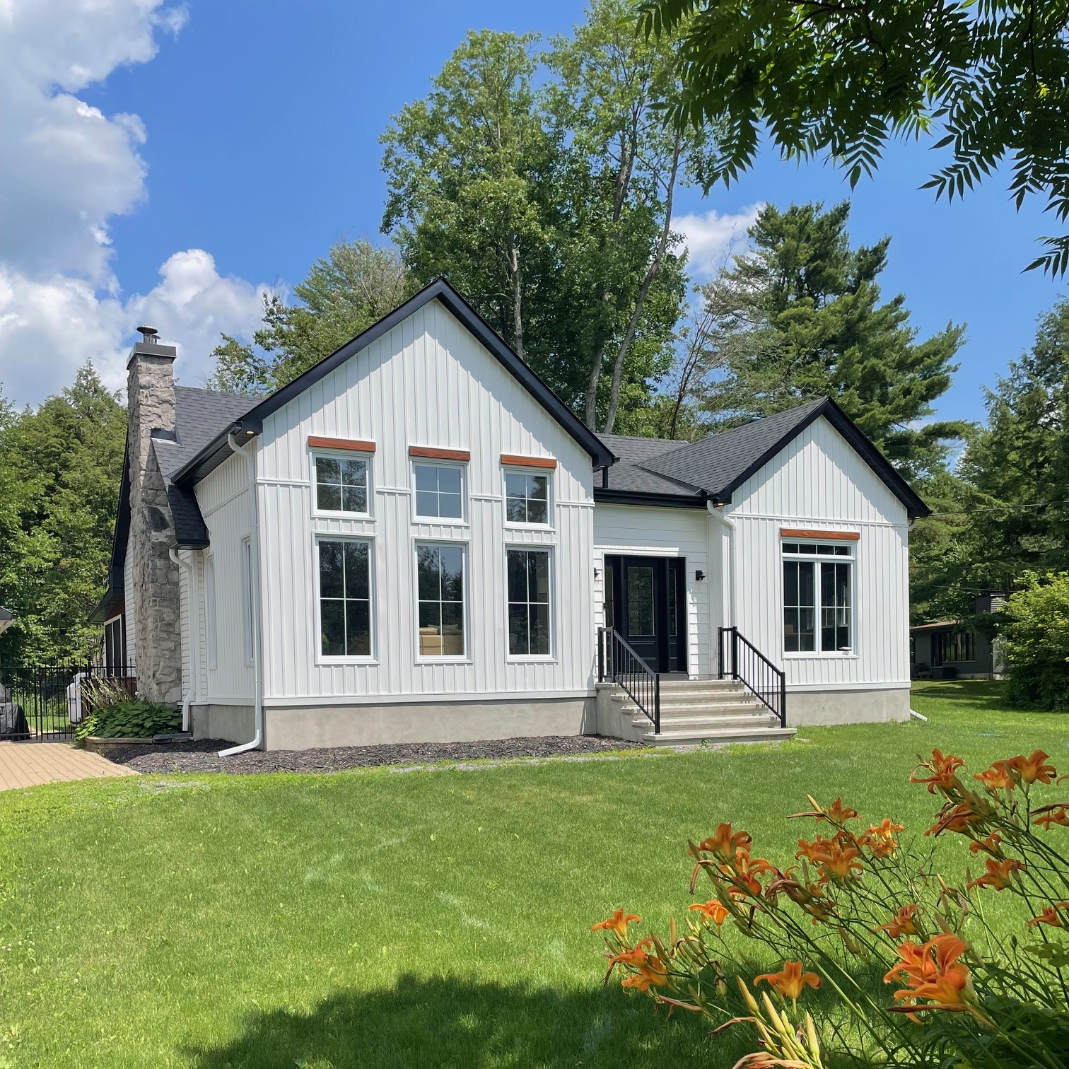 White modern home siding project in Ottawa with black roof and stone chimney